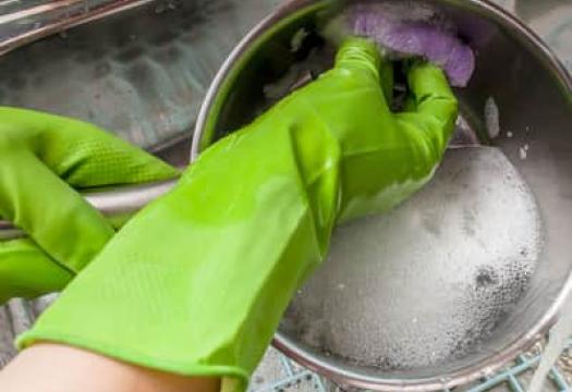Person cleaning pan with gloves on