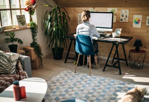 Woman working at home office with dog.