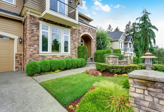 Beautiful curb appeal of American house with stone trim and perfectly trimmed shrubs | Merry Maids