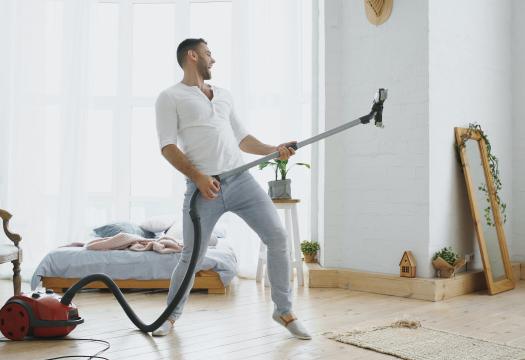 Man playing air guitar on vacuum while cleaning house