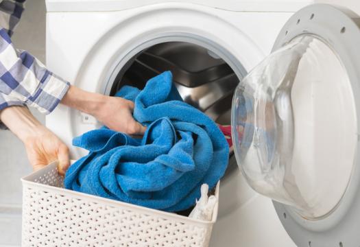 Person’s hand put dirty clothes in the washing machine | Merry Maids